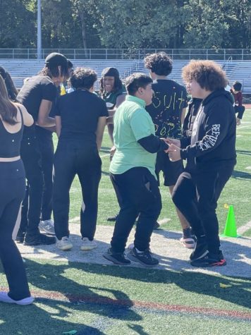 Seniors and juniors dance and stand on the field.